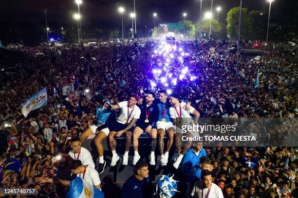 Argentina's captain and forward Lionel Messi holds the FIFA World Cup Trophy on board a bus as he celebrates alongside teammates and supporters after...