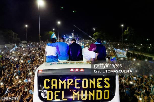 Argentina's players celebrate on board a bus with a sign reading "World Champions" with supporters after winning the Qatar 2022 World Cup tournament...