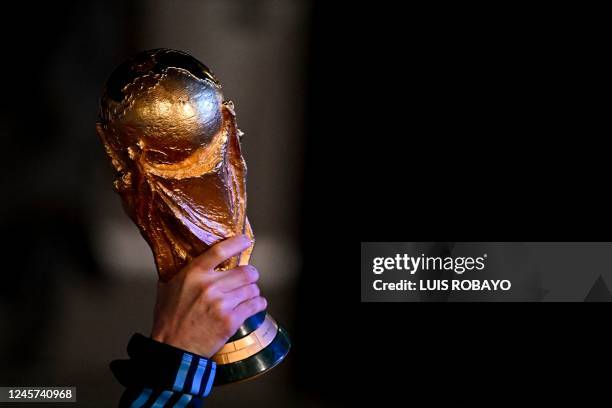 Argentina's captain and forward Lionel Messi holds the FIFA World Cup Trophy upon arrival at Ezeiza International Airport after winning the Qatar...