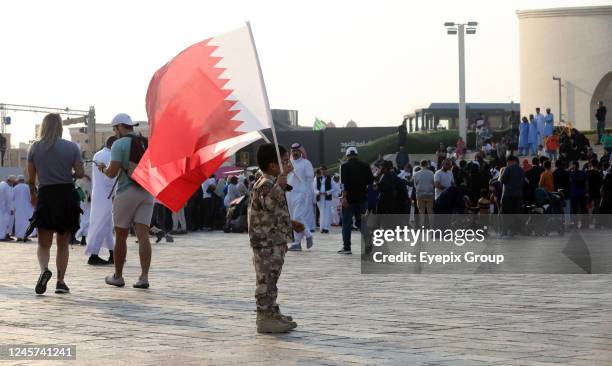 Boy holds the national flag of Qatar during the National Day celebrations and final FIFA World Cup 2022 match between Argentina and France....