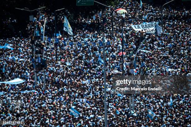 Fans of Argentina climb light posts as a multitude gather for the victory parade of the Argentina men's national football team after winning the FIFA...