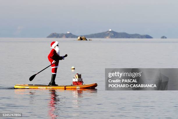 Woman dressed as Santa Claus steers a paddleboard close to the Mare e Sol beach in Pietrosella on December 20, 2022 on the French Mediterranean...