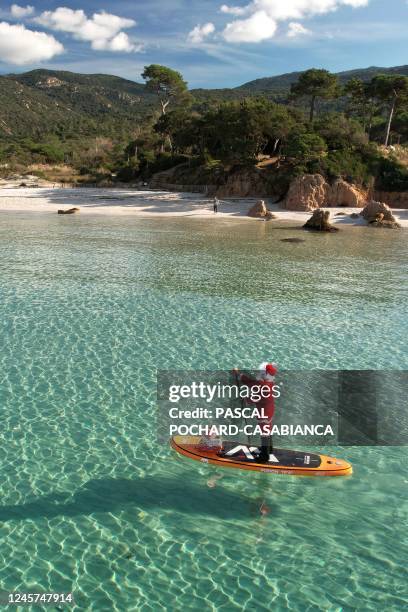 This aerial photograph shows a woman dressed as Santa Claus steering a paddleboard close to the Mare e Sol beach in Pietrosella on December 20, 2022...