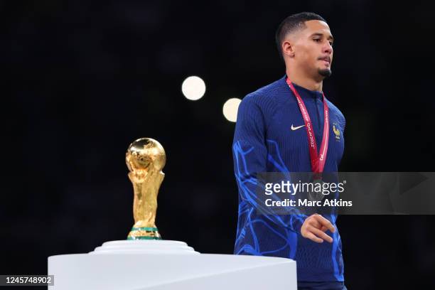William Saliba of France looks dejected as he walks past the World Cup trophy during the FIFA World Cup Qatar 2022 Final match between Argentina and...