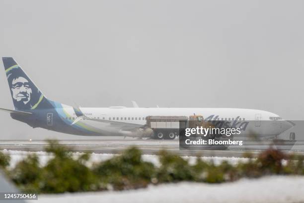 Snow plow next to an Alaska Airlines plane during a snow storm at Seattle-Tacoma International Airport in Seattle, Washington, US, on Tuesday, Dec....