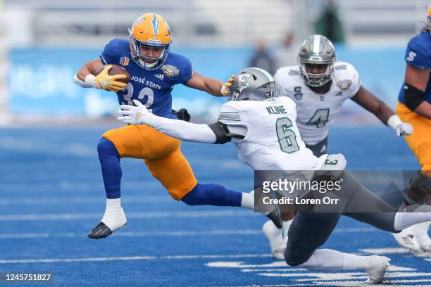 Running back Kairee Robinson of the San Jose State Spartans pushes off the tackle attempt of linebacker Chase Kline of the Eastern Michigan Eagles...