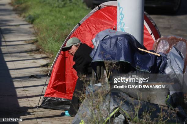 An unhoused person sits next to their tent along Glendale Boulevard in Los Angeles, California, December 19, 2022. - A state of emergency over...