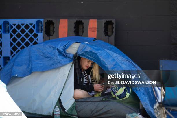 An unhoused person sits in their tent on the sidewalk in Skid Row in Los Angeles, California, December 19, 2022. - A state of emergency over...
