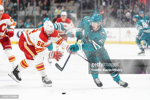 Oskar Lindblom of the San Jose Sharks skates with the puck against MacKenzie Weegar of the Calgary Flames at SAP Center on December 20, 2022 in San...