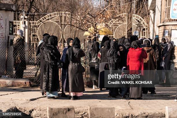 Afghan female university students stop by Taliban security personnel stand next to a university in Kabul on December 21, 2022. - Afghanistan's...