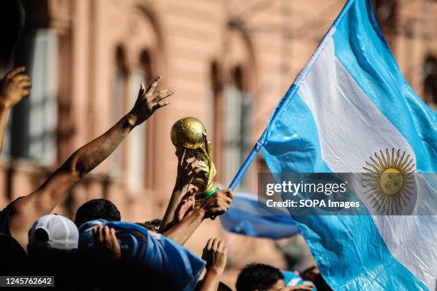 Argentine fans display a replica of the World Cup next to the Argentine flag during the victory celebration in the Plaza de Mayo. More than 4 million...