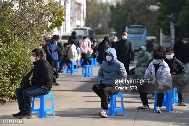People queue outside a makeshift clinic transformed from a bus in Nanjing, in China's eastern Jiangsu province on December 21, 2022. - China OUT /...