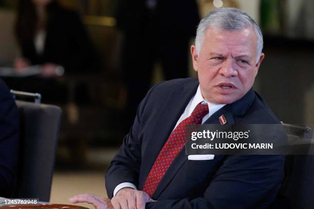 King Abdullah II of Jordan listens to the speech of France's President during a working lunch at the royal Al-Husseiniya Palace in Amman on December...