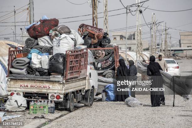Members of an Iraqi family pack their belongings in the back of a pickup truck as they prepare to return home and move out of the Jadaa camp for the...