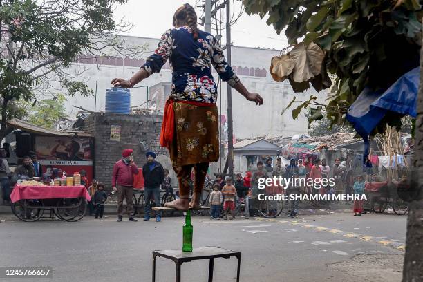 Girl performs a balancing act as a part of a street circus wherein artists perform various stunts to attract small monetary contributions from...