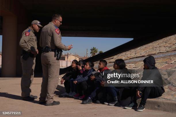 Migrants wait to be processed by US Border Patrol after crossing into the United States from Mexico via a hole cut in the border fence in El Paso,...