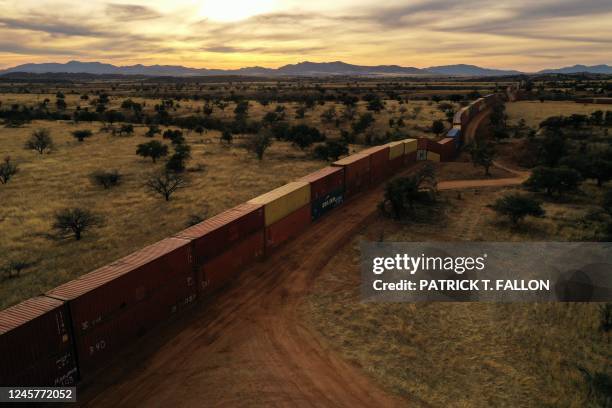 Border wall constructed of shipping containers and topped with concertina wire, built on federal land by Republican governor Doug Ducey, stands along...