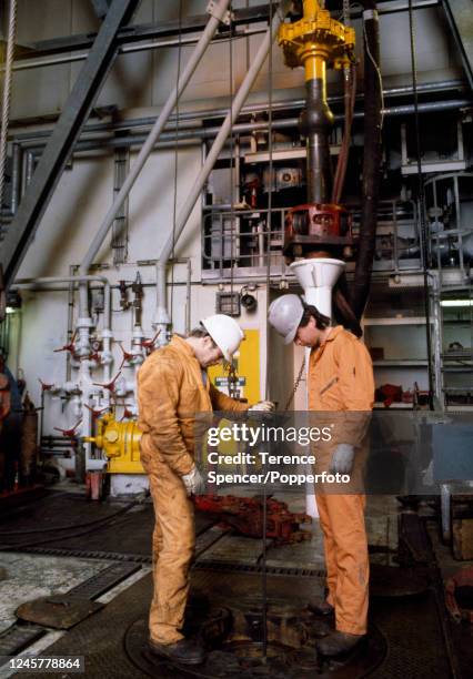 Two men checking the umbilical to the underwater television cameras on the North West Hutton Oil Rig in the North Sea, circa June 1983.