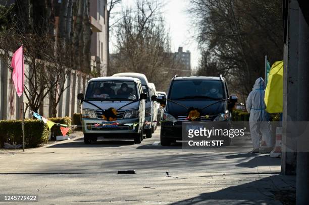 Hearses are seen waiting to enter a crematorium in Beijing on December 22, 2022. - Hospitals are struggling, pharmacy shelves have been stripped bare...