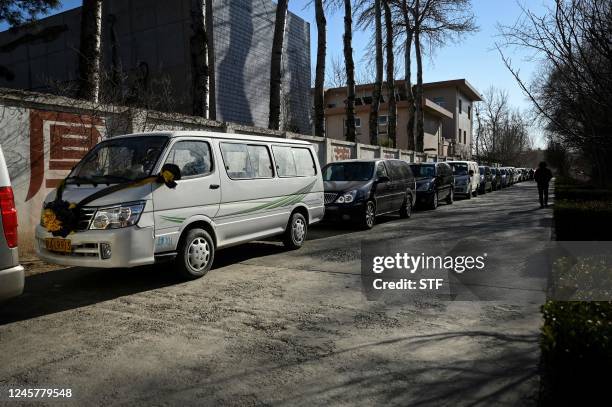 Hearses are seen waiting to enter a crematorium in Beijing on December 22, 2022. - Hospitals are struggling, pharmacy shelves have been stripped bare...