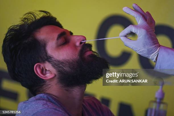 Health worker collects a swab sample for Covid-19 coronavirus screening from a passenger arriving on an international flight at Anna International...