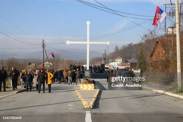People, as they hold flags and banners, gather near a village for a demonstration to protest the Government of Kosovo and support Kosovo Serbs who...