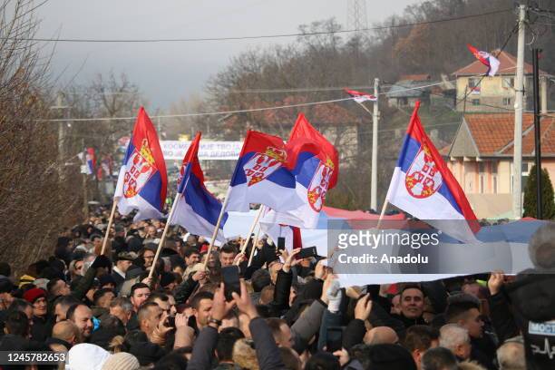 People, as they hold flags and banners, gather near a village for a demonstration to protest the Government of Kosovo and support Kosovo Serbs who...