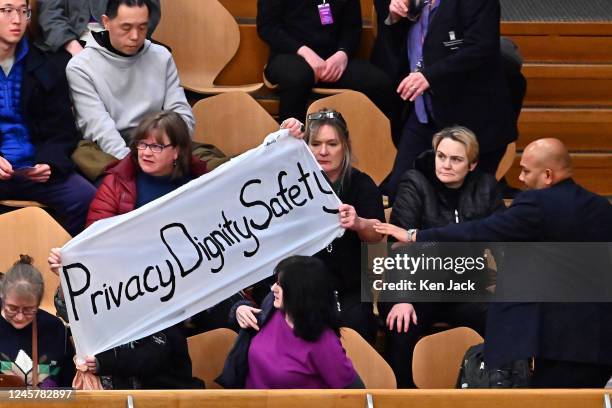 Protesters display a banner in the public gallery of the Scottish Parliament, as the vote on the controversial Gender Recognition Reform Bill was...