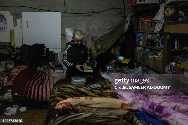 Hleb Petrova looks at his books in a basement where he takes shelter and live with her family, relatives and neighbours seeking more protection due...