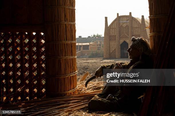 Man smokes a cigarette as he sits at the entrance of a reed house known as a mudhif, along Iraq's southern marshes of Chibayish in Dhi Qar province...