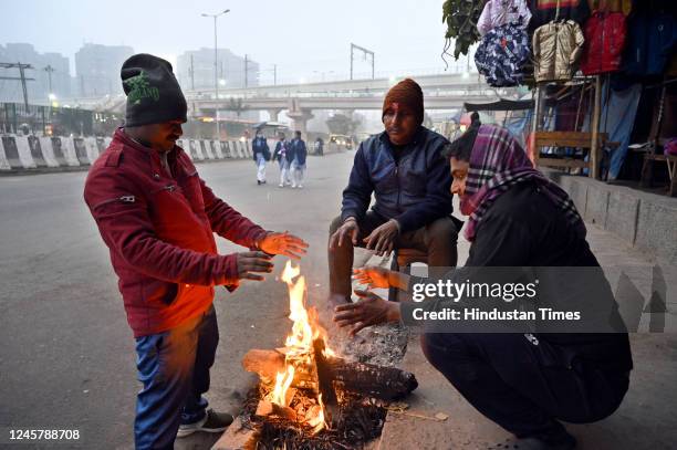 People huddled around a bonfire during morning hours amid cold weather at ISBT Anand Vihar, on December 22, 2022 in New Delhi, India. Delhi along...