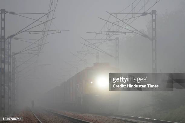 Passenger train runs through cold and foggy weather towards Gurugram to Delhi railway station at Sarai Alawardi Village near Palam Vihar on December...