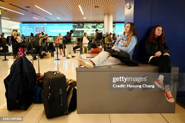 Hannah Monday right, and her sister Katelyn sit on the box after their flight canceled at Denver International Airport in Denver, Colorado on...