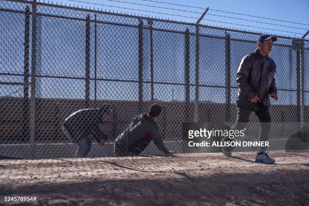 Migrants illegally cross into the US via a hole in a fence in El Paso, Texas, on December 22, 2022. - The US Supreme Court halted December 19, 2022...