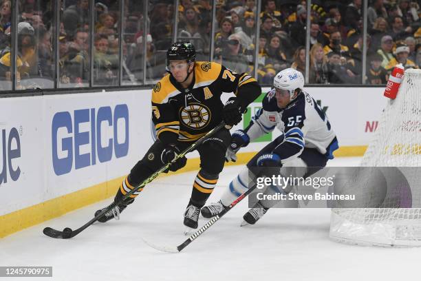 Charlie McAvoy of the Boston Bruins skates with the puck against Mark Scheifele of the Winnipeg Jets at the TD Garden on December 22, 2022 in Boston,...