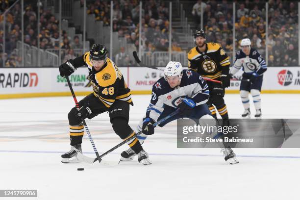 Matt Grzelcyk of the Boston Bruins skates with the puck against Karson Kuhlman of the Winnipeg Jets at the TD Garden on December 22, 2022 in Boston,...