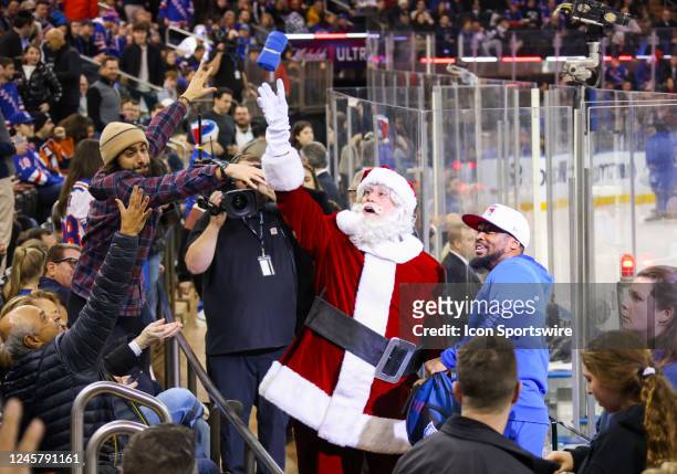 Santa Claus throws T-Shirts to the crowd during the National Hockey League game between the New York Islanders and the New York Rangers on December...