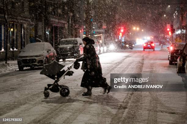 Person crosses a street in the Mile End, a borough in Montreal, Quebec, Canada, as the snow comes down on December 22, 2022. - A...