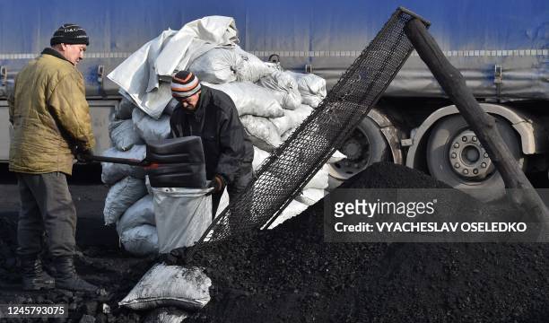 Workers stack bags of coal at the Suluktu sorting base, some 1100 km from Bishkek, Kyrgyzstan on December 12, 2022. - Nestled in the foothills of...