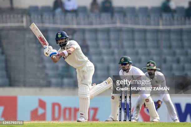 India's Virat Kohli plays a shot as Bangladesh's Nurul Hasan watches during the second day of the second cricket Test match between Bangladesh and...