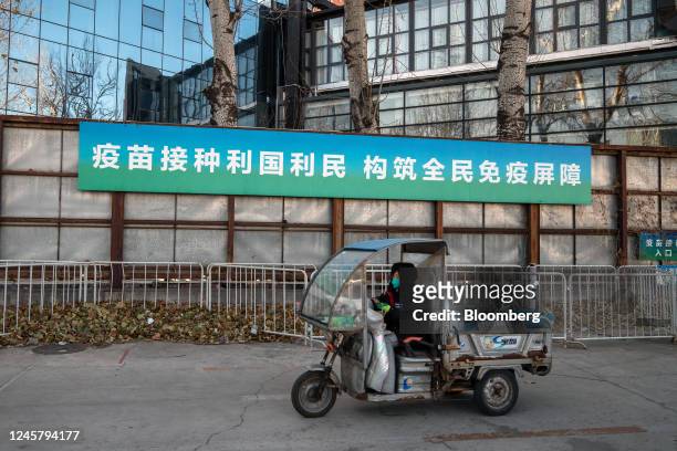 Motorist travels past a banner promoting Covid vaccination in Beijing, China, on Friday, Dec. 23, 2022. China's soaring Covid infections are keeping...