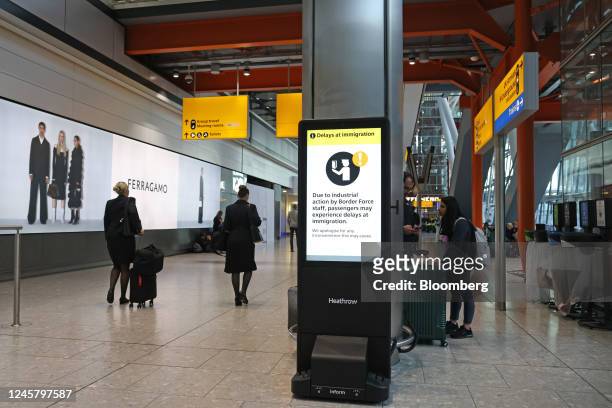 Airline staff pass a passenger notice warning of delays due to Border Force strike action at Heathrow Airport Terminal 5 in London, UK, on Friday,...