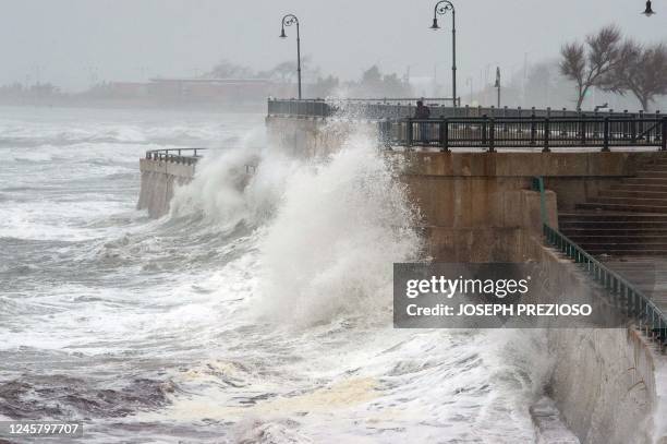 Man watches as large waves crash over the seawall in Lynn, Massachusetts on December 23, 2022. - A historic and brutal winter storm put some 240...