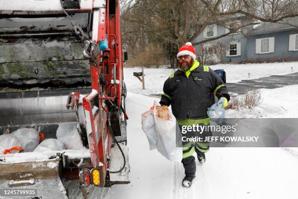 Sanitation worker Randy Allensworth collects trash on a blustery day at a home in Bloomfield Hills, Michigan on December 23, 2022. - A...