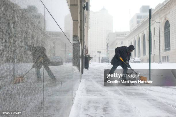 Man tries to remove snow from the sidewalk in downtown Detroit on December 23, 2022 in Detroit, United States. A major winter storm swept over much...