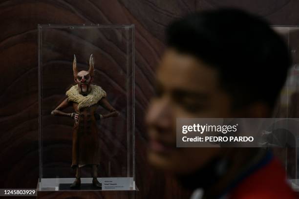 Teenager is seen next to a statuette of the character Count Volpe from the movie Pinocchio by Mexican director Guillermo del Toro exhibited at the...