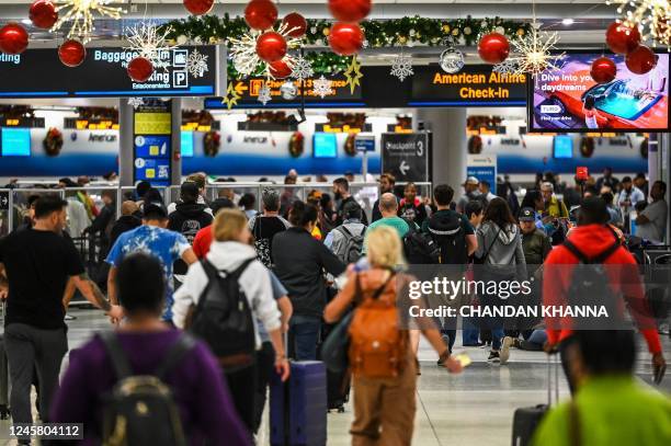 Travelers walk through Miami International Airport during a winter storm ahead of the Christmas holiday in Miami, Florida, on December 23, 2022. -...