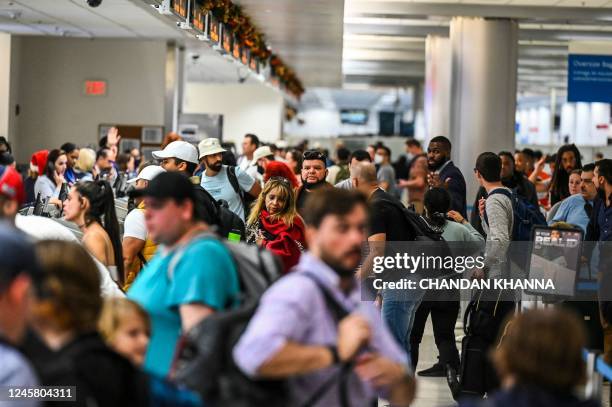 Travelers wait in line to check in at Miami International Airport during a winter storm ahead of the Christmas holiday in Miami, Florida, on December...