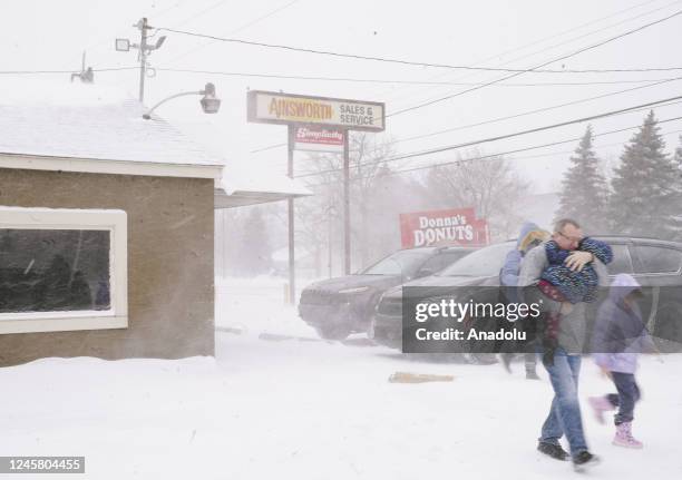 Family huddled together, moves quickly to their car, to get out of the frigid cold from a massive winter storm affecting most of the USA., in Flint,...