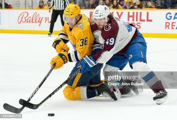 Samuel Girard of the Colorado Avalanche defends against Cole Smith of the Nashville Predators during an NHL game at Bridgestone Arena on December 23,...